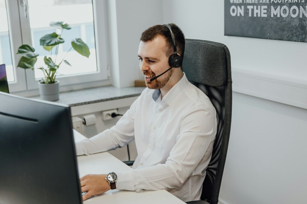 a man wearing a headset sitting in front of a computer